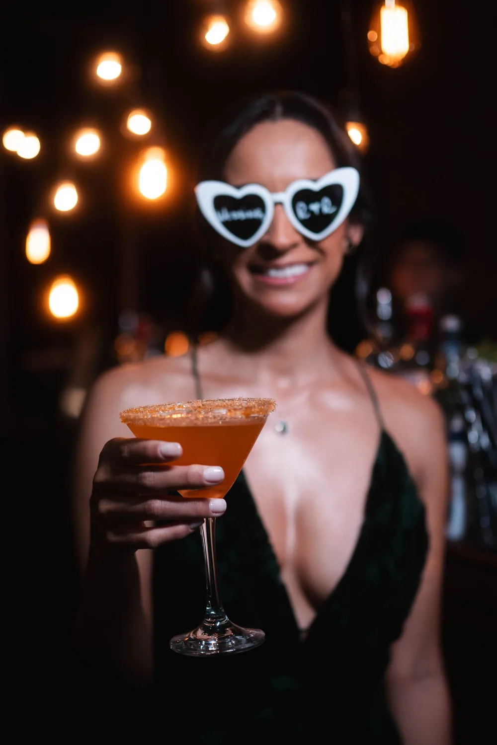 Convidada de óculos de coração erguendo um drink